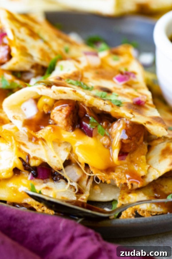 A photo of a slice of teriyaki chicken quesadilla garnished with minced red onion and chopped fresh cilantro.