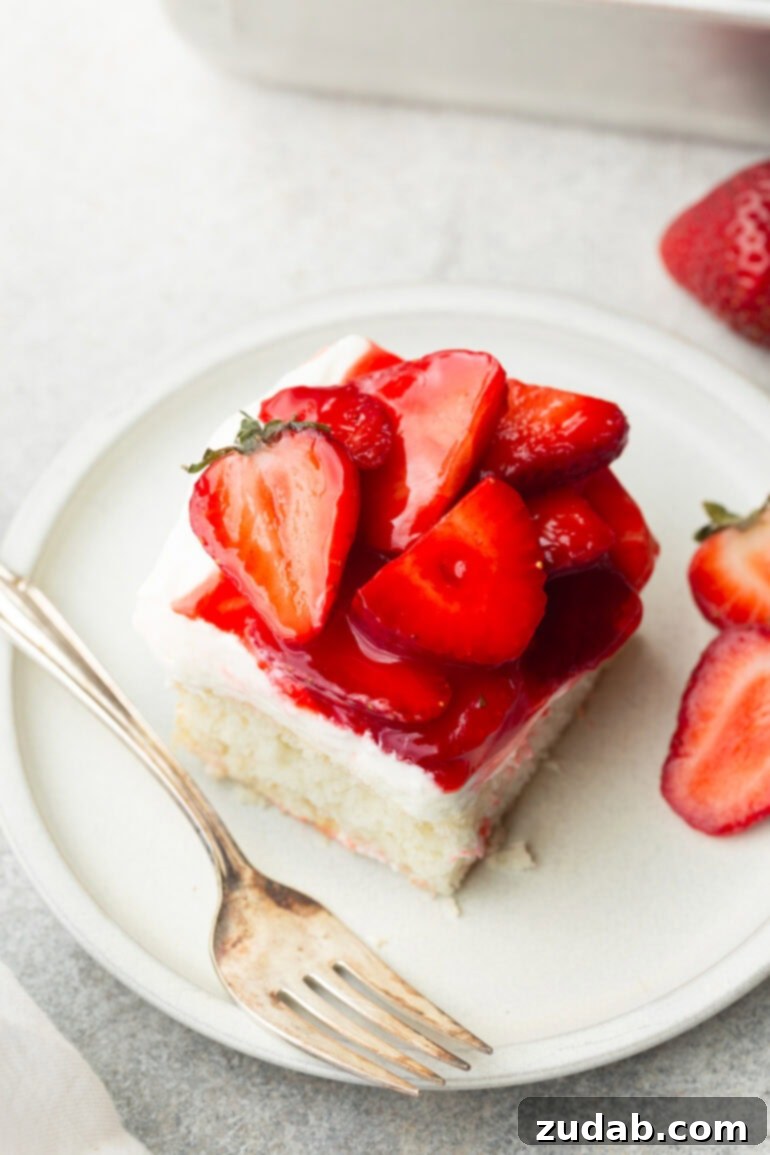 Simple Strawberry Shortcake 7 A stunning overhead photo of a piece of moist white cake, exquisitely topped with fluffy cream cheese frosting and artfully arranged, glossy sliced strawberries. This delectable dessert, featuring layers of fluffy cake, fresh strawberries, and creamy whipped cream, is guaranteed to satisfy any sweet tooth.