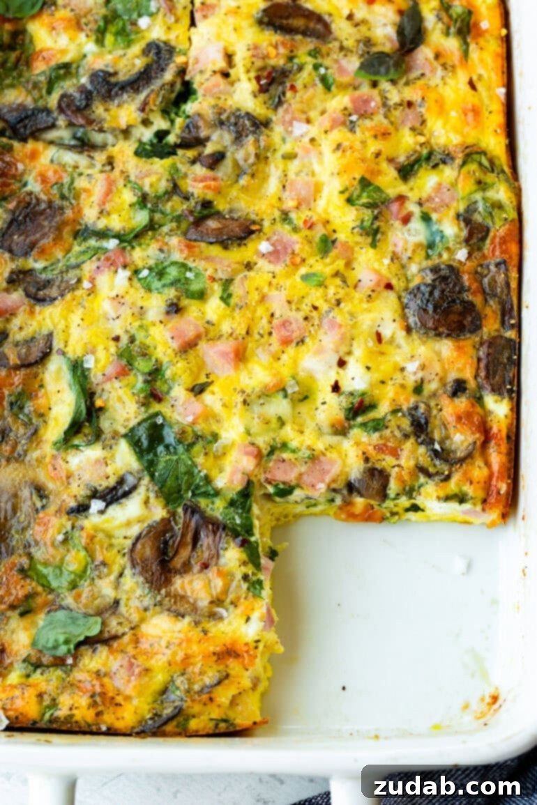 Morning Magic: Ham, Cheese, and Mushroom Egg Bake 5 A baked breakfast egg casserole with a piece missing.