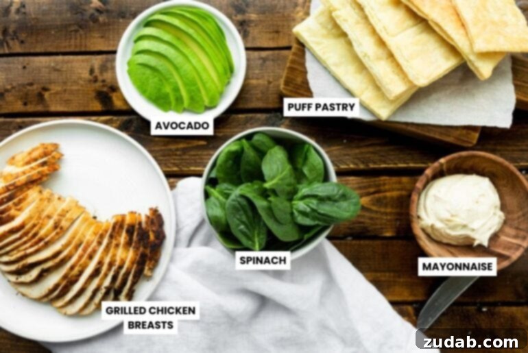 Zesty Grilled Chicken Avocado Stack 4 A photo showcasing all the fresh ingredients laid out for making the Grilled Chicken Avocado Napoleons: golden puff pastry squares, vibrant baby spinach, thinly sliced grilled chicken, creamy avocado slices, and a small bowl of spicy mayo, ready for assembly.