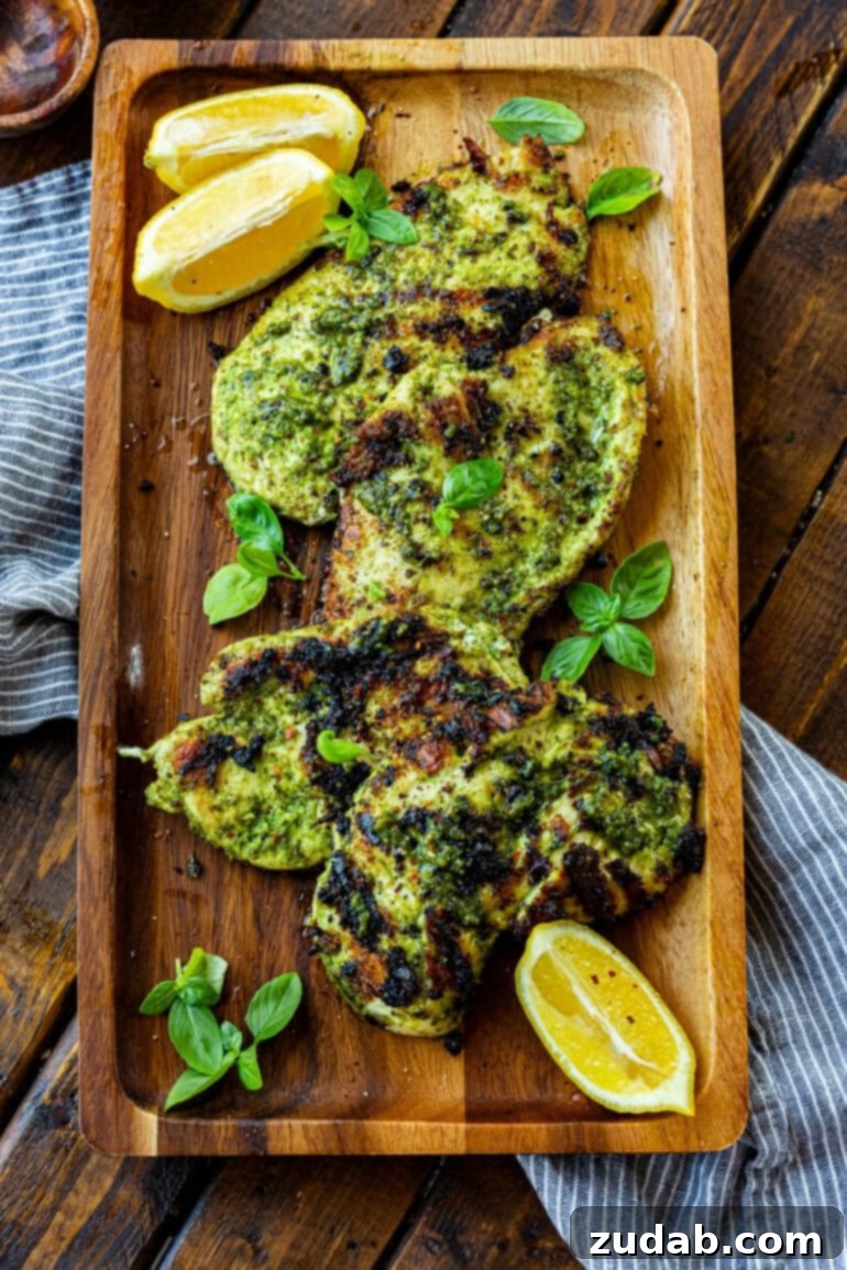 Golden Crispy Pesto Chicken 3 a photo of a large wooden serving board with grilled pesto chicken breasts and lime wedges sitting on it.