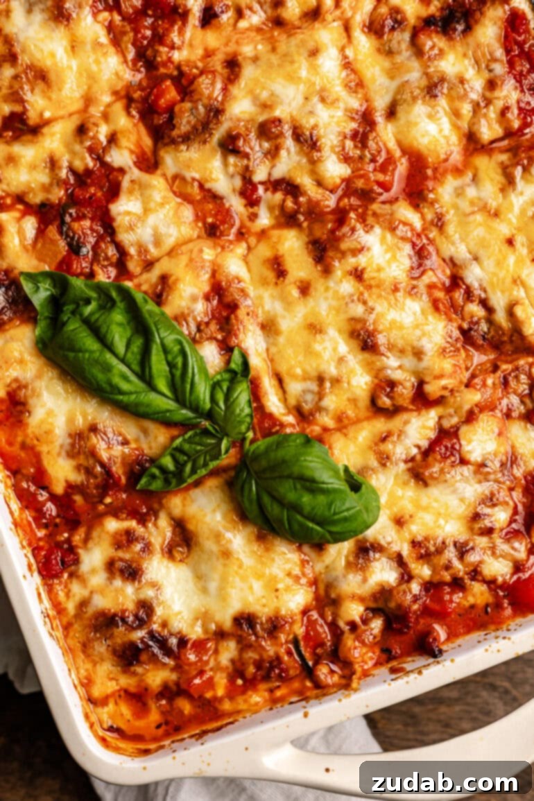 Perfect Zucchini Lasagna No Soggy Layers 15 A pan of layered veggie noodles, cheese, and meat sauce that has been baked in the oven with a basil garnish.