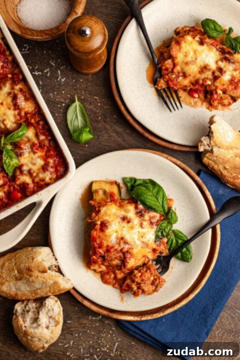 The BEST zucchini lasagna we've ever had! ohsweetbasil.com two plates are sitting aside a large baking dish full of zucchini lasagna. each of the plates has a large serving of the dish and a fork.