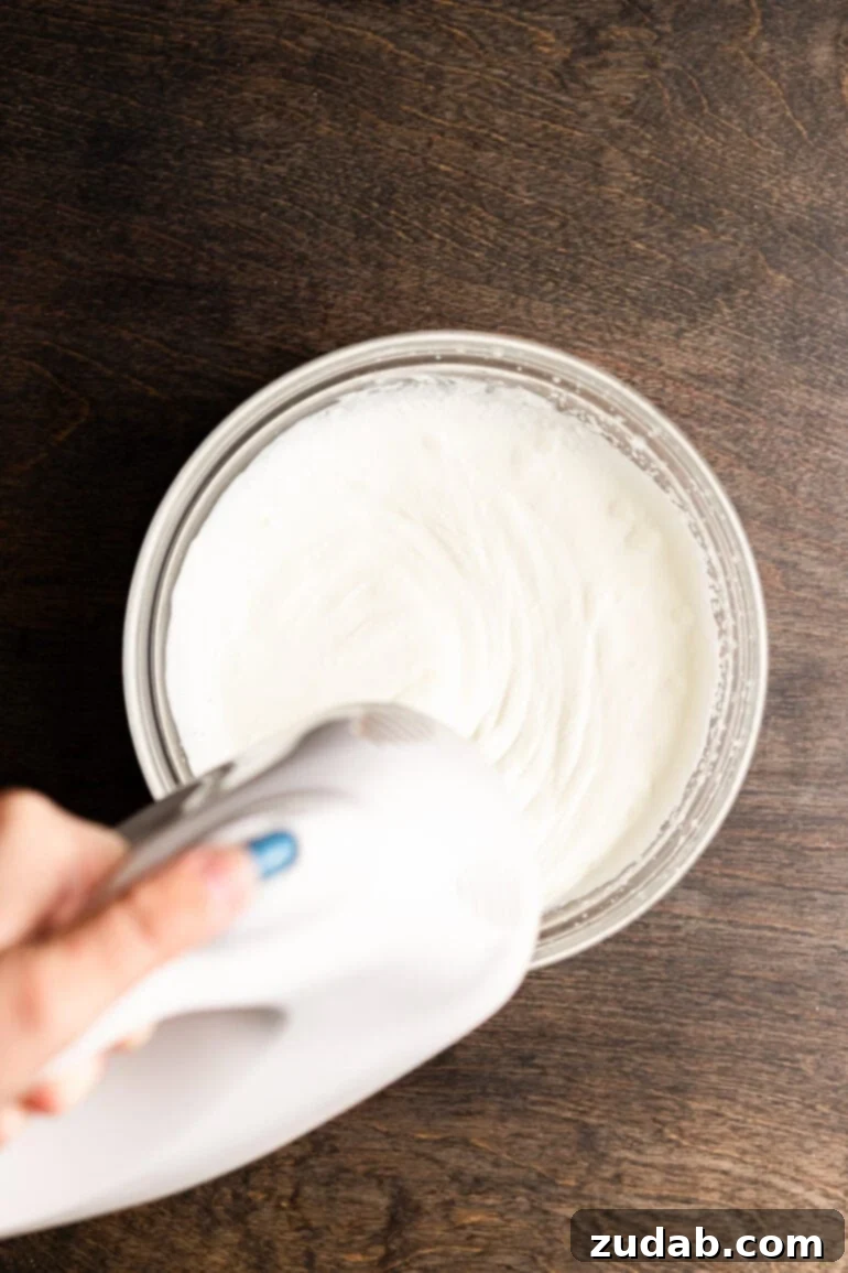 Step 12: Gently folding a portion of whipped cream into the mango mixture.