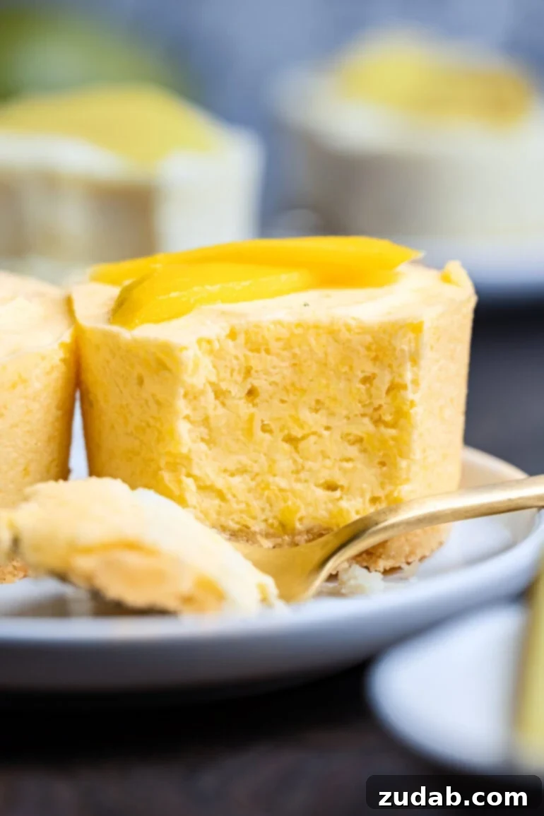 A beautifully presented individual frozen mango pie, with a fork removing a perfect bite, showcasing the creamy filling and crunchy crust, garnished with fresh mango slices.