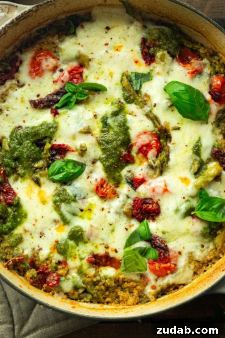 Pratik Tek Tavada Pesto Kuşkonmazlı Kinoa 3 a photo of a pesto asparagus casserole topped with melted mozzarella cheese and whole fresh basil leaves