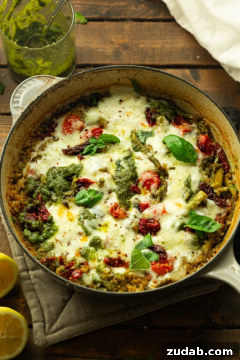 Pratik Tek Tavada Pesto Kuşkonmazlı Kinoa 8 a photo taken over the top of a pesto asparagus quinoa topped with melted mozzarella cheese and whole fresh basil leaves