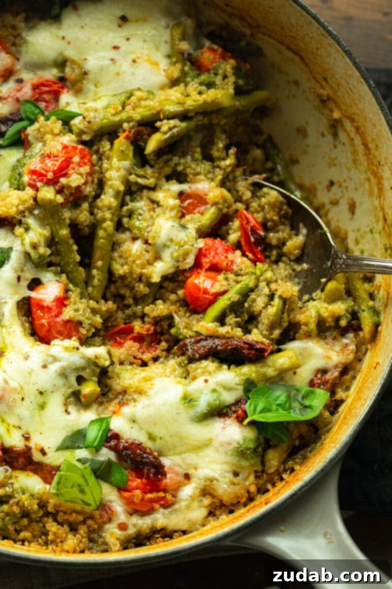 Pratik Tek Tavada Pesto Kuşkonmazlı Kinoa 10 a photo of a large metal serving spoon removing a scoop of pesto quinoa with asparagus from a large skillet