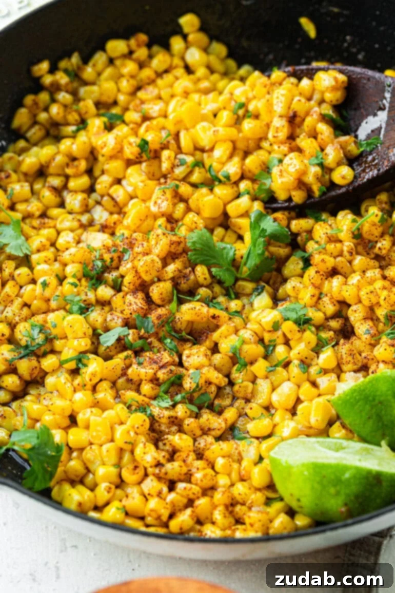 Easy 5-Minute Honey Lime Skillet Corn 4 A serving spoon scooping honey butter skillet corn from the pan, with fresh chopped cilantro sprinkled on top, showcasing its delicious glaze.