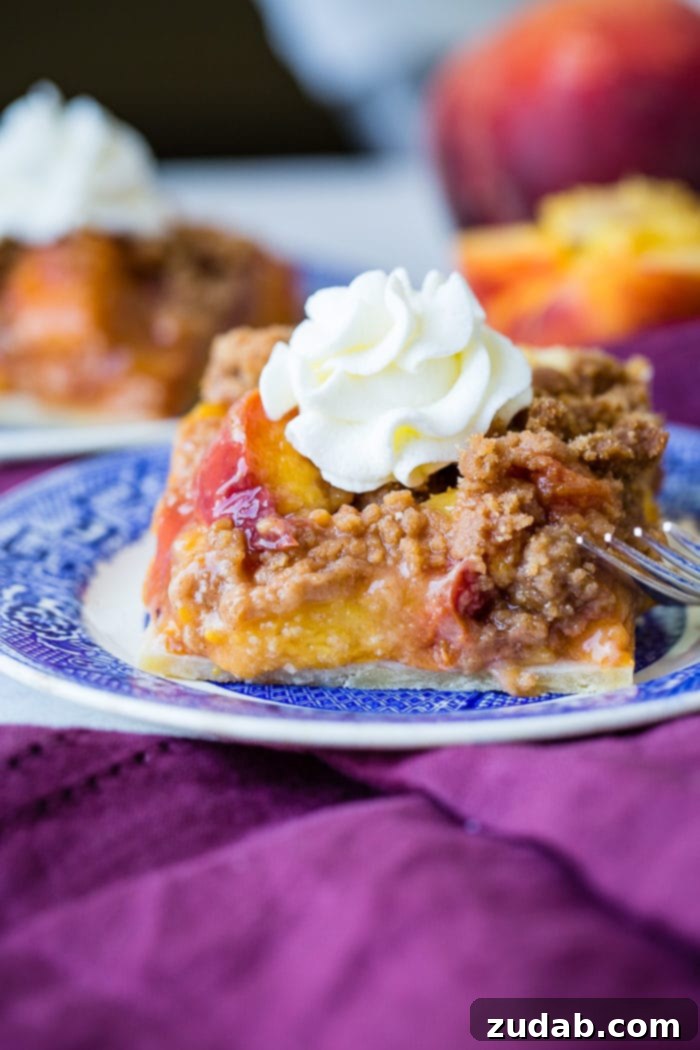 Golden Peach Crumble Squares 7 A purple napkin under a vibrant blue china designed dessert plate with a slice of brown sugar peach pie bars