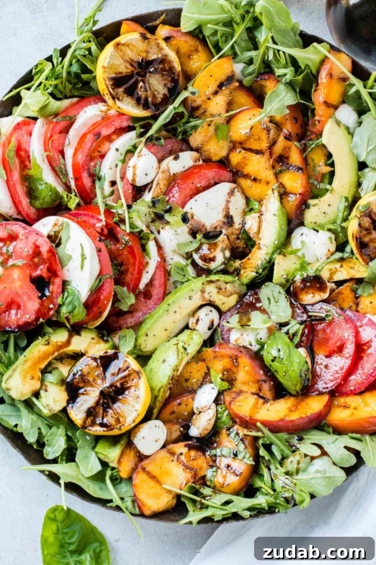 Grilled Peach Caprese 2 A vibrant Grilled Peach Caprese Salad with fresh ingredients including grilled peaches, mozzarella, tomatoes, avocado, and balsamic glaze.