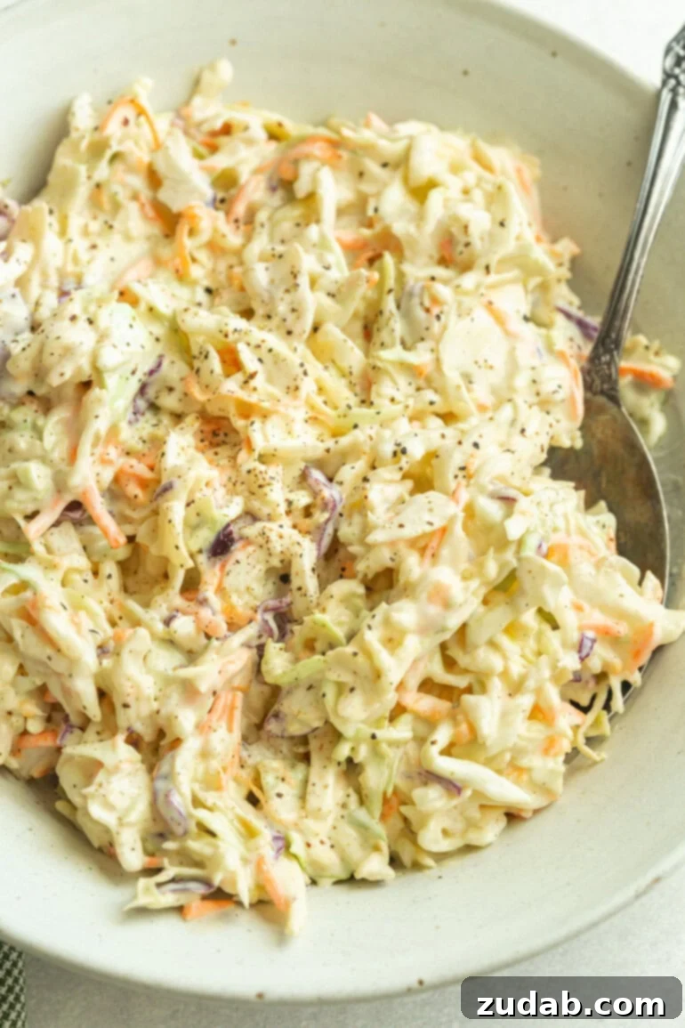 The Secret to Amazing Homemade Coleslaw 2 A heaping bowl of creamy homemade coleslaw, made with crisp green cabbage, vibrant shredded carrots, and a tangy mayo-based dressing. Ideal for barbecues and picnics.