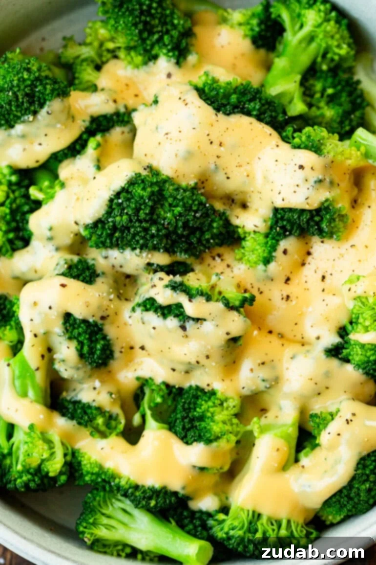 bright green broccoli florets topped with creamy cheddar cheese sauce and salt and pepper