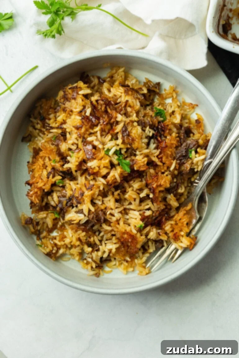 A close-up angle of the baked rice served in a bowl with two forks, showing the glossy, buttery finish and golden-brown edges. You can see the texture clearly, soft, crispy, savory, and packed with flavor, ready to be enjoyed.
