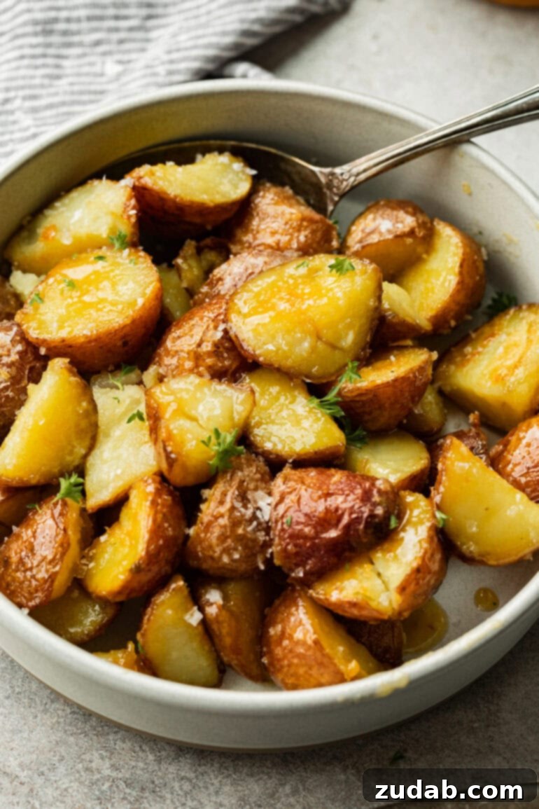 Golden Roasted Red Potatoes 4 Perfectly crispy, caramelized red potatoes are elegantly arranged in a minimalist white bowl, their golden edges sharply contrasting with the pristine white, showcasing their irresistible texture.