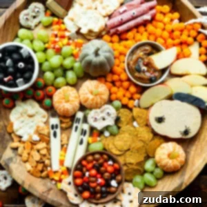 A large circular wooden charcuterie board filled with Halloween themed snacks, highlighting the festive arrangement and variety of treats.