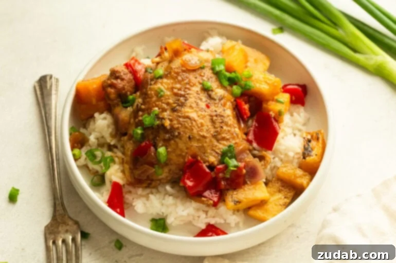 Sweet and Tangy Slow Cooker Pineapple Chicken 2 A serving of white rice topped with golden slow cooker pineapple chicken, pineapple chunks, chopped red bell pepper, and onions, garnished with fresh green onions