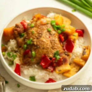 Sweet and Tangy Slow Cooker Pineapple Chicken 9 A serving of white rice topped with golden slow cooker pineapple chicken, pineapple chunks, chopped red bell pepper, and onions
