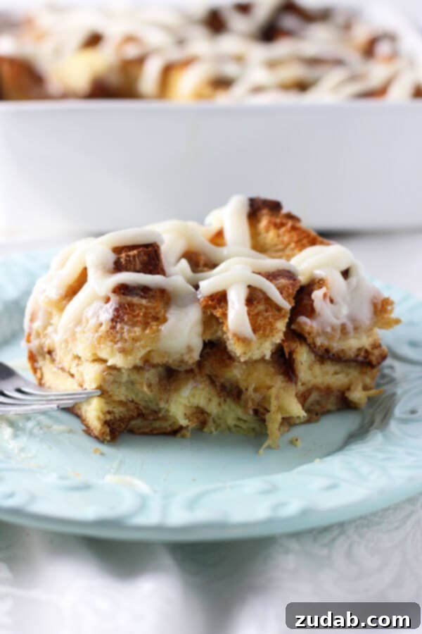 Gooey Caramel Cinnamon Roll Baked French Toast Casserole for breakfast or brunch A slice of Gooey Caramel Cinnamon Roll Baked French Toast Casserole topped with cream cheese frosting, ready for a delicious breakfast