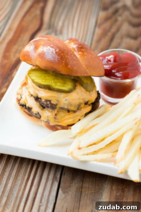 Two Secrets to the Ultimate Burger 4 Juicy grilled hamburger with melted cheese, lettuce, tomato, and fries on a white plate