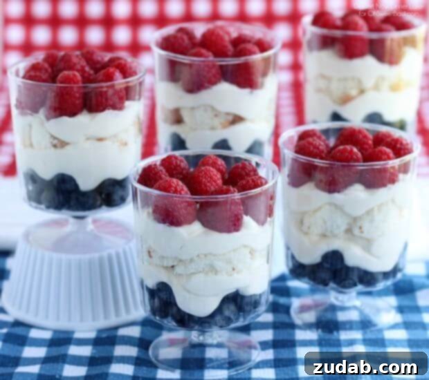 No-Bake Patriotic Trifle Dessert for Crowds Individual Patriotic Trifle desserts in clear glasses arranged on a white tray for a 4th of July celebration