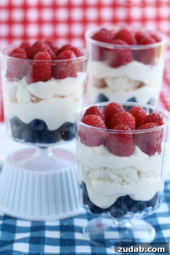 Make-Ahead Dessert Idea for Summer Holidays Close-up of a hand holding an individual Patriotic Trifle glass, showing the layers of cake, cream, and berries