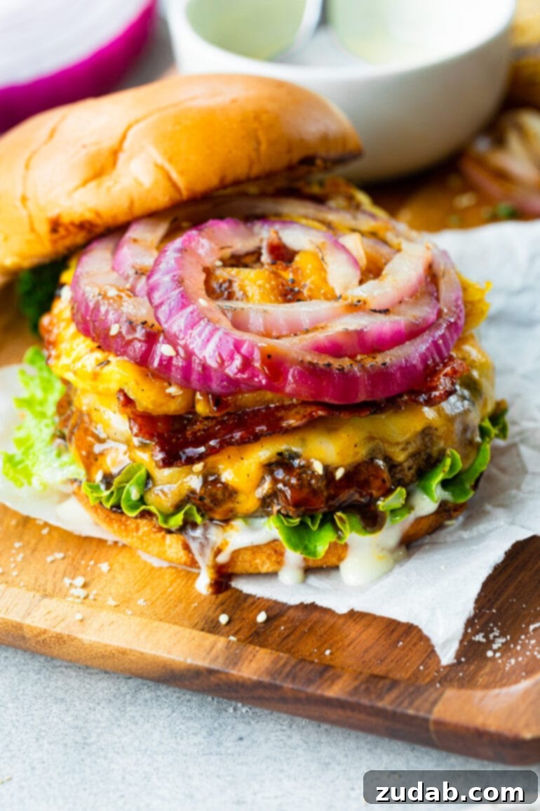 Teriyaki Pina Colada Burger 4 A beautifully grilled cheeseburger, with the top bun removed to showcase a vibrant array of toppings: a thick slice of red onion, a golden grilled pineapple ring, and perfectly crispy bacon, all melting into the cheese on a juicy patty.