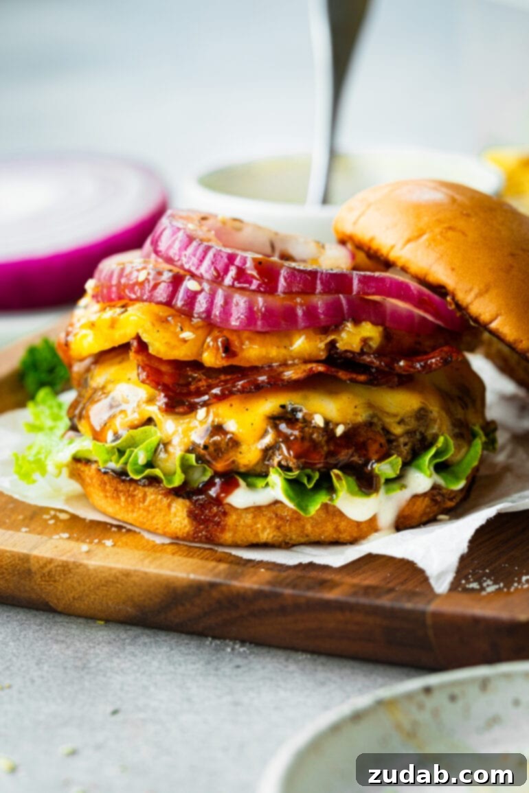 Teriyaki Pina Colada Burger 5 A perfectly assembled gourmet burger, featuring a grilled patty, melted cheese, crisp bacon, vibrant green lettuce, and a thick slice of grilled pineapple, all nestled between toasted buns.