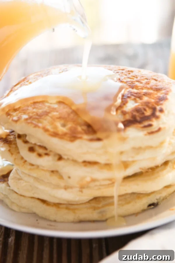 The absolute best recipe (after testing hundreds) for buttermilk pancakes. In fact, these are melt in your mouth buttermilk pancakes! A visually stunning and utterly mesmerizing shot of rich, warm buttermilk syrup being generously and slowly poured over a towering, magnificent stack of golden, fluffy buttermilk pancakes. This creates an enticing, cascading waterfall of sweetness that is absolutely perfect for an indulgent breakfast, a leisurely brunch, or even a delightful dessert, promising a sensory feast.