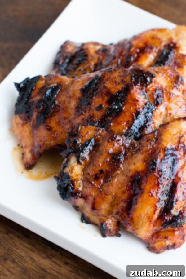 Oh my goodness, this chicken!! Sticky honey lime grilled chicken is our new favorite! ohsweetbasil.com Close-up of golden-brown sticky honey lime grilled chicken, garnished with fresh lime wedges.