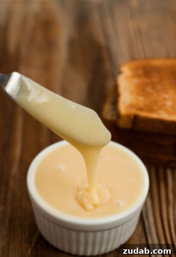 The best blasted honey butter ever. ohsweetbasil.com A close-up shot of the incredibly smooth and golden homemade honey butter, glistening in a white bowl.
