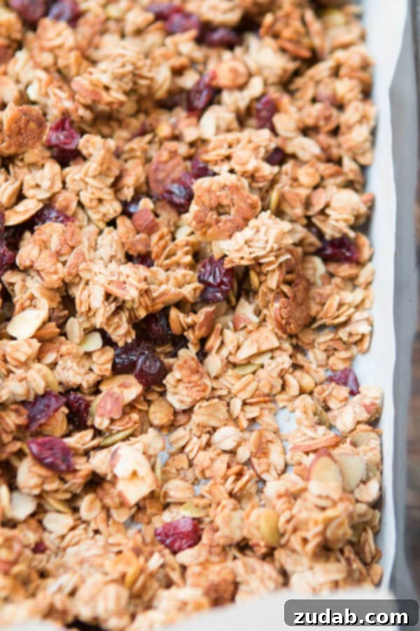 Perfectly Baked Strawberry Almond Granola Clusters Close-up of golden brown strawberry almond granola on a baking sheet, showing crunchy clusters.