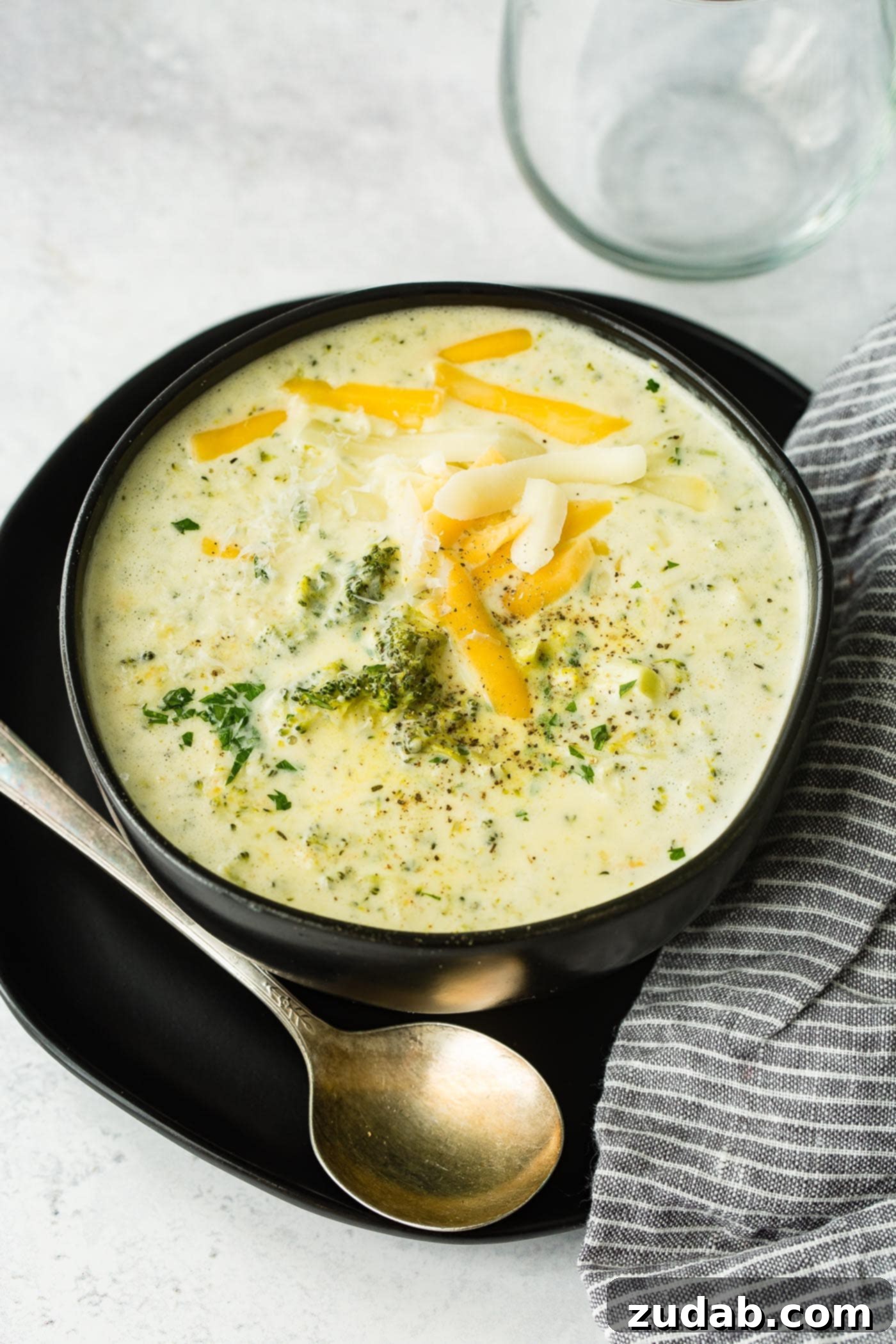 Cozy Slow Cooker Broccoli Cheddar Bliss 3 A black bowl full of crockpot broccoli cheddar soup with extra cheese on top, ready to be served.