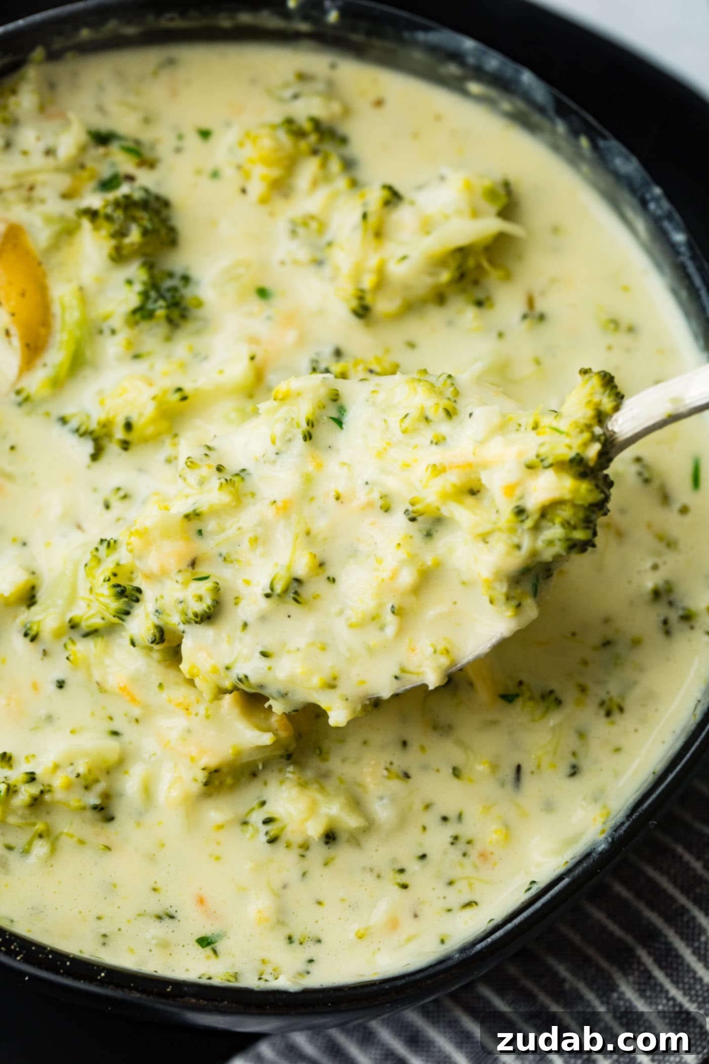 Cozy Slow Cooker Broccoli Cheddar Bliss 4 A black bowl full of slow cooker broccoli cheese soup with extra cheese on top, enticingly presented.