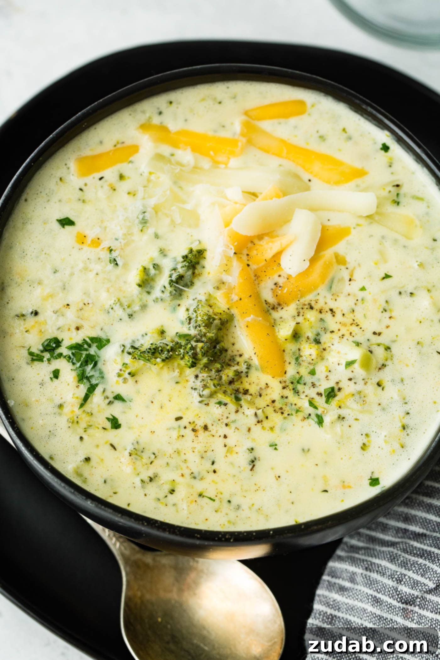 Cozy Slow Cooker Broccoli Cheddar Bliss 6 A black bowl full of crockpot broccoli cheese soup with extra cheese on top, ready to serve.