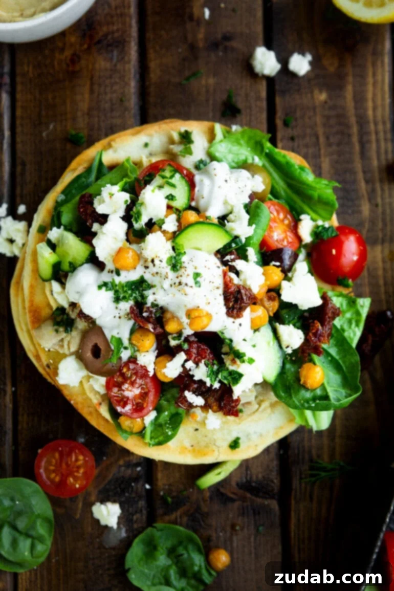 Vibrant Greek Turkey or Chicken Tostadas 3 a photo taken over the top of a greek tostada topped with cucumber, tomatoes, chickpeas, olives, feta and tzatziki sauce.
