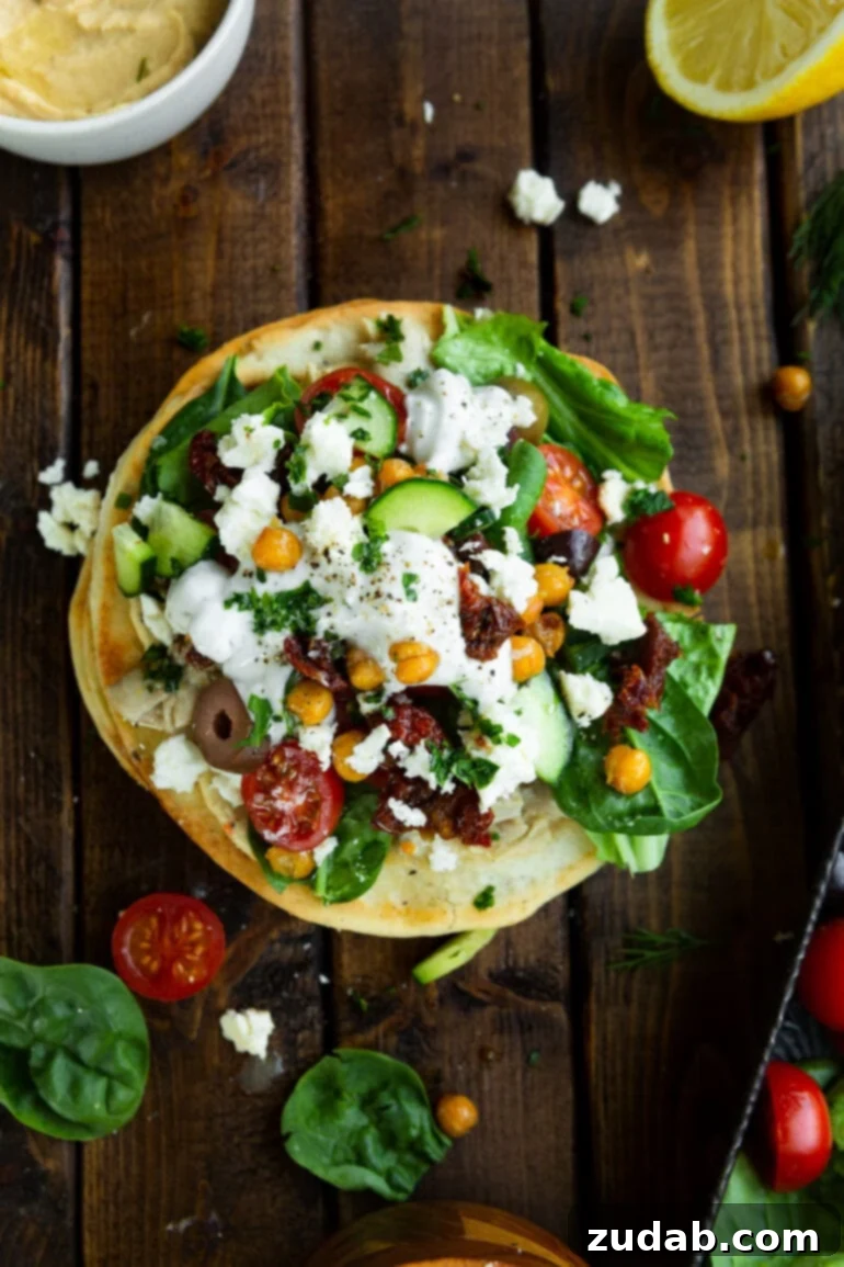 Vibrant Greek Turkey or Chicken Tostadas 7 a photo taken over the top of greek chicken tostada toped with cherry tomatoes, lettuce, olives, roasted chickpeas, cucumbers and tzatziki sauce.