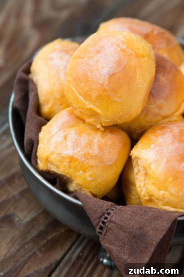 Freshly Baked Sweet Potato Rolls: A Delight for Any Occasion A close-up of a basket overflowing with freshly baked, warm sweet potato rolls, ready for serving.