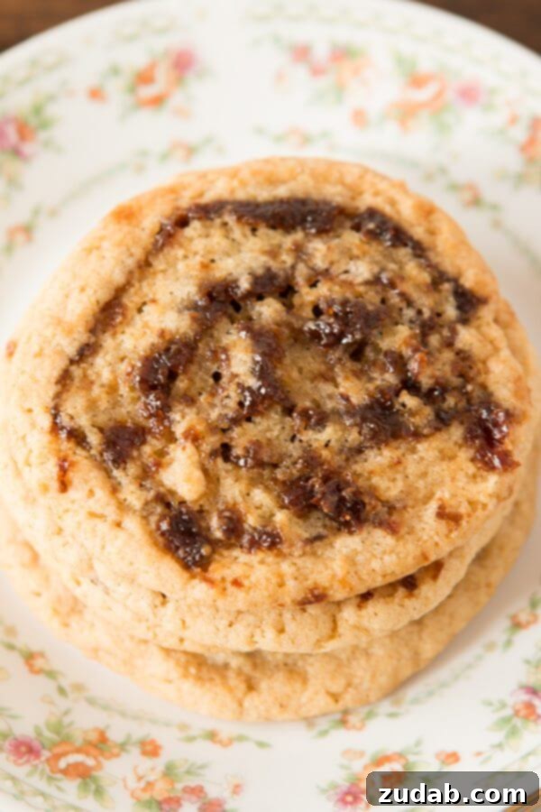 Enjoy these delightful Pinwheel Cookies, a beloved family recipe that brings joy to every occasion. A charming stack of three Pinwheel Cookies resting on a floral patterned plate, ready to be enjoyed.