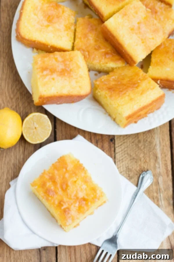 This Lemon Jello Cake is perfect for anytime of the year. The fresh tastes of summer or to brighten the winter holiday meals. Multiple slices of Lemon Jello Cake on a large white plate, with an additional slice on a smaller white plate atop a white napkin, creating an appetizing display.