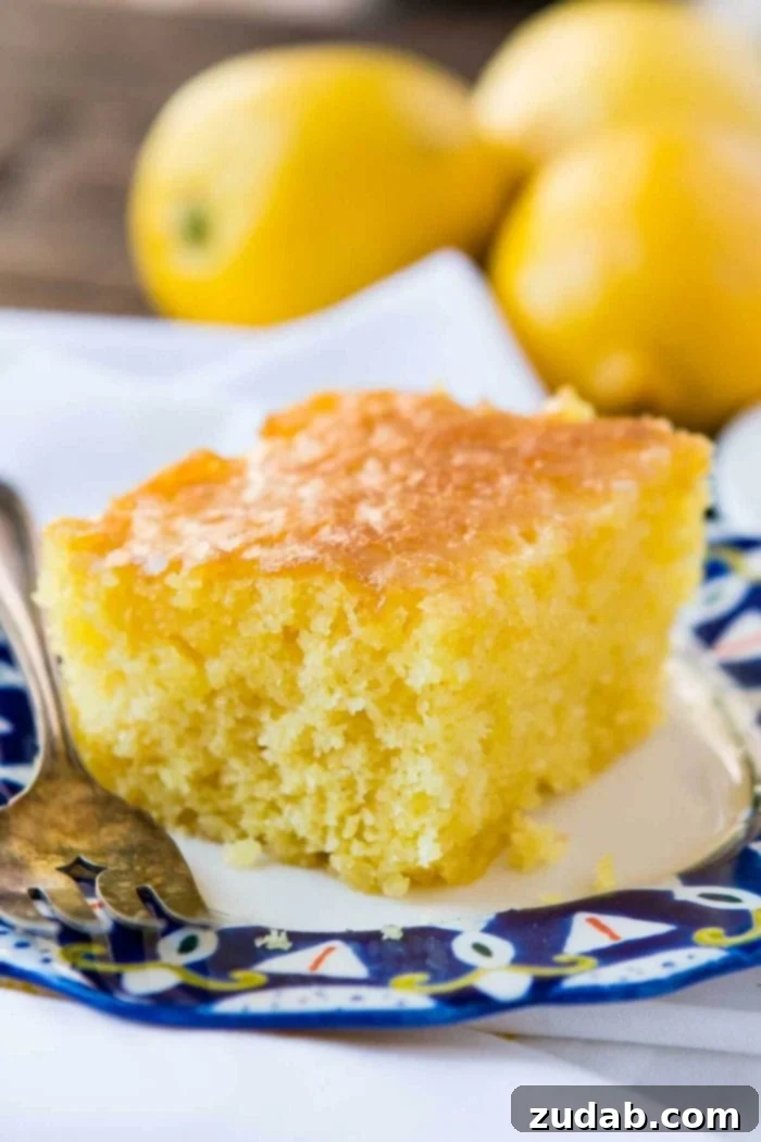 This Lemon Jello Cake is perfect for anytime of the year. The fresh tastes of summer or to brighten the winter holiday meals. A mouthwatering slice of Lemon Jello Cake on a napkin, accompanied by a silver fork, inviting a bite.