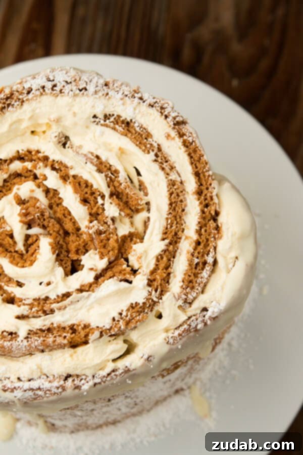Indulge in the Creamy Goodness of Our Pumpkin Roll White Chocolate Cake Close-up of a festive Pumpkin Roll White Chocolate Cake slice, revealing the creamy white chocolate filling.