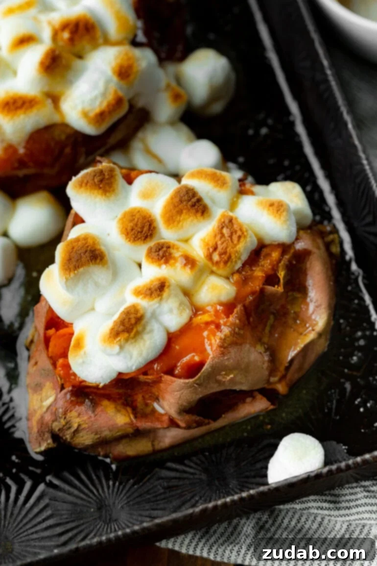 The Ultimate Homemade Texas Roadhouse Loaded Sweet Potato 2 A photo of a baked sweet potato topped with butter and toasted mini marshmallows, ready to be enjoyed.