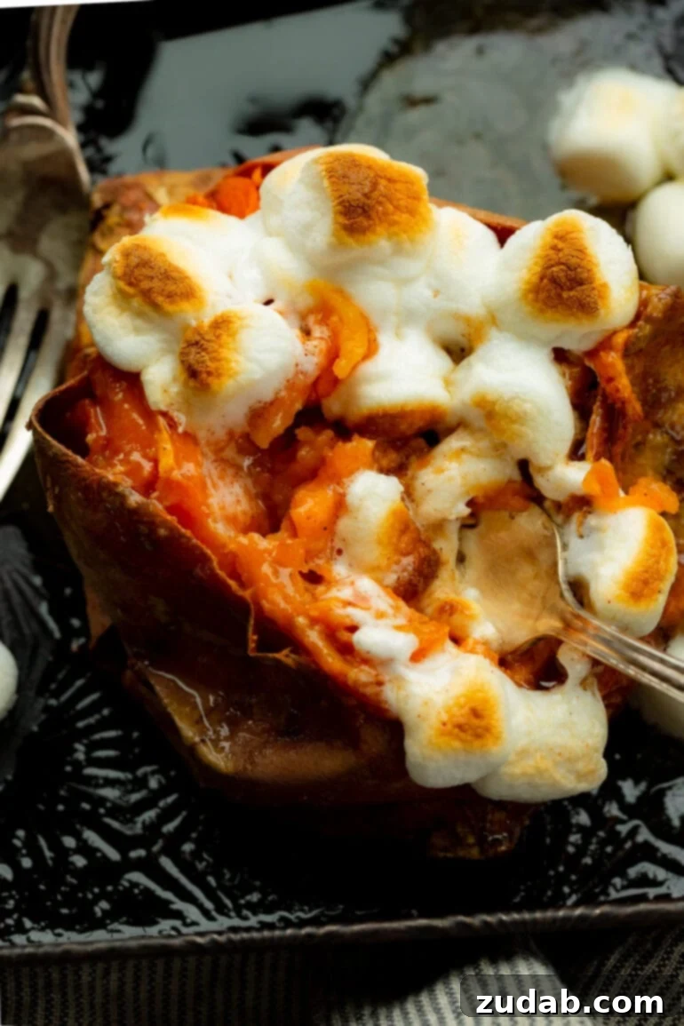 The Ultimate Homemade Texas Roadhouse Loaded Sweet Potato 7 A fork digging into a baked sweet potato topped with roasted mini marshmallows, capturing a perfect gooey bite.