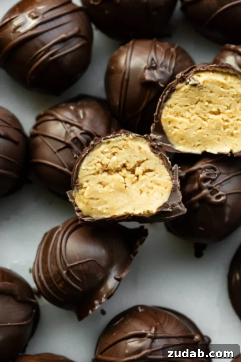 Peanut Butter Chocolate Bliss Bites 2 A close-up photo of several dark chocolate-covered peanut butter balls, with two sliced in half to reveal the creamy peanut butter filling inside. Perfect for a party dessert or sweet snack.