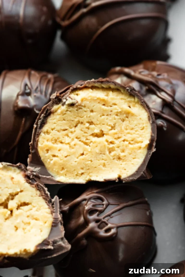 Peanut Butter Chocolate Bliss Bites 7 A mouth-watering close-up of a dark chocolate-coated peanut butter truffle, perfectly cut in half to showcase its creamy, inviting interior.