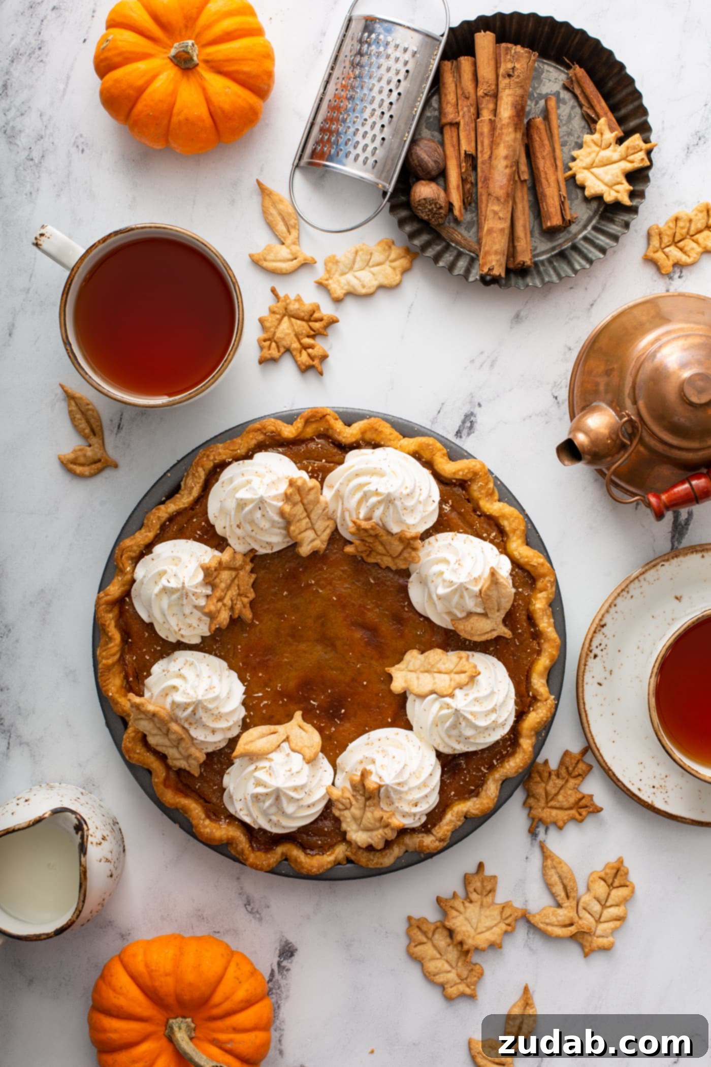Homestyle Pumpkin Pie 7 A photo of a pumpkin pie topped with piped whipped cream and stamped pie crust leaves taken from above.