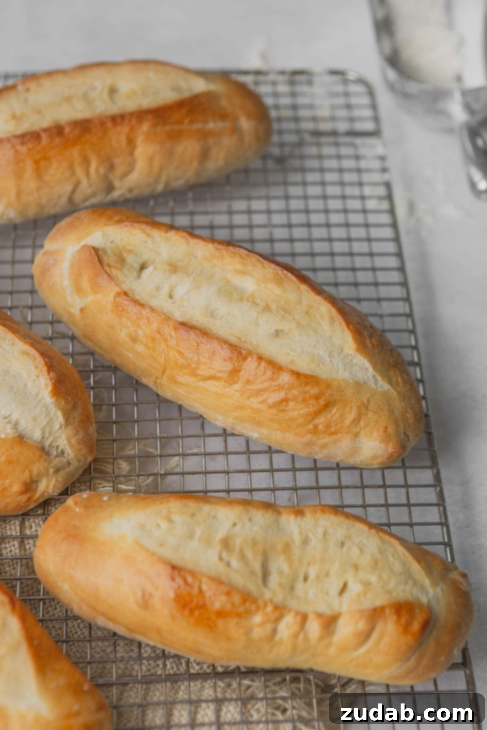 Homemade Hoagie Rolls Made Easy 3 Four golden hoagie rolls on a wire cooling rack.