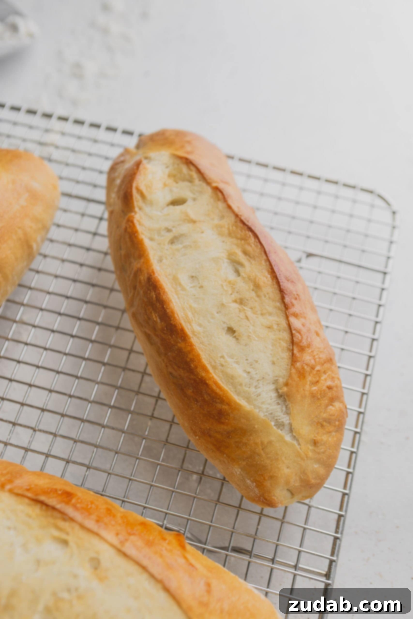 Homemade Hoagie Rolls Made Easy 5 A hoagie roll on a wire cooling rack. the roll is baked to a golden brown.
