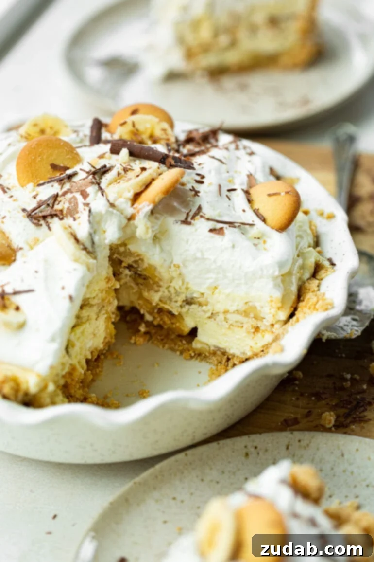Heavenly No-Bake Banana Pudding Pie with Nilla Wafer Crust 4 A close-up photo of a thick, creamy banana cream pudding pie in a white baking dish, with one slice carefully removed to reveal the luscious layers inside.